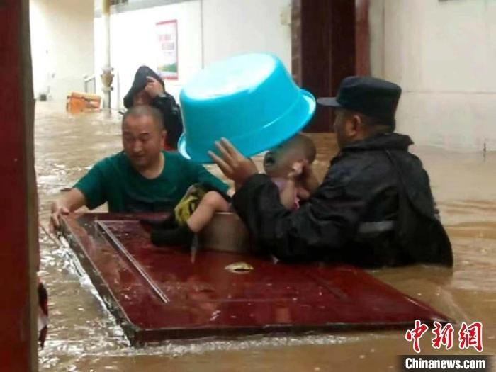 “山西晋城迎强降雨 民警以盆作“伞”转移被困小孩